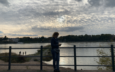 Frau mit Handy im Gegenlicht am Rhein